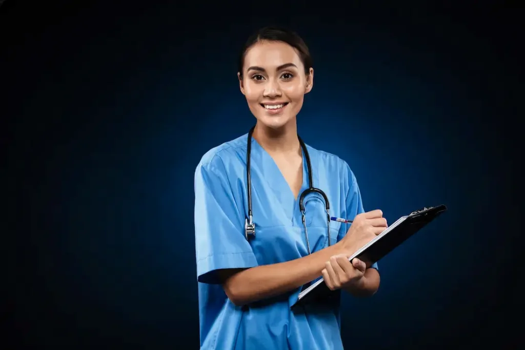 Nursing Assistant student in blue medical uniform holding a patient file during healthcare training in Kerala